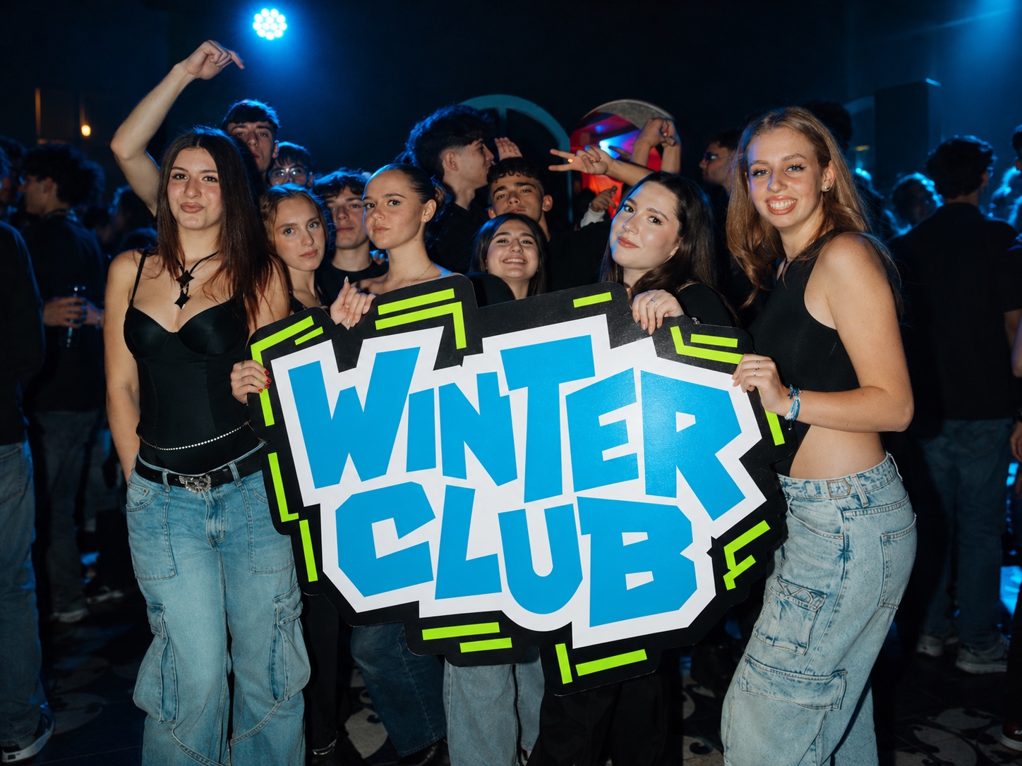 Gruppo di ragazzi in discoteca con il cartellone WINTER CLUB